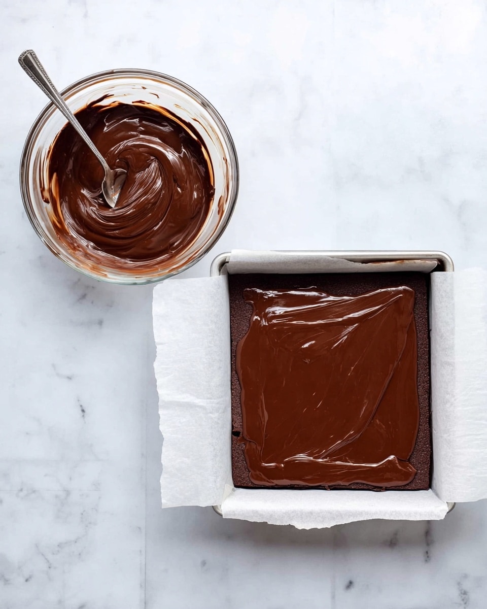 The image shows two side-by-side views. On the left, there is a clear glass bowl filled with smooth, dark brown melted chocolate, with a silver spoon resting inside the bowl. On the right, a square baking pan lined with white parchment paper holds a thick, glossy layer of the same dark chocolate spread evenly on top of a base layer which is just visible at the edges. Both setups are placed on a white marbled surface. photo taken with an iphone --ar 4:5 --v 7