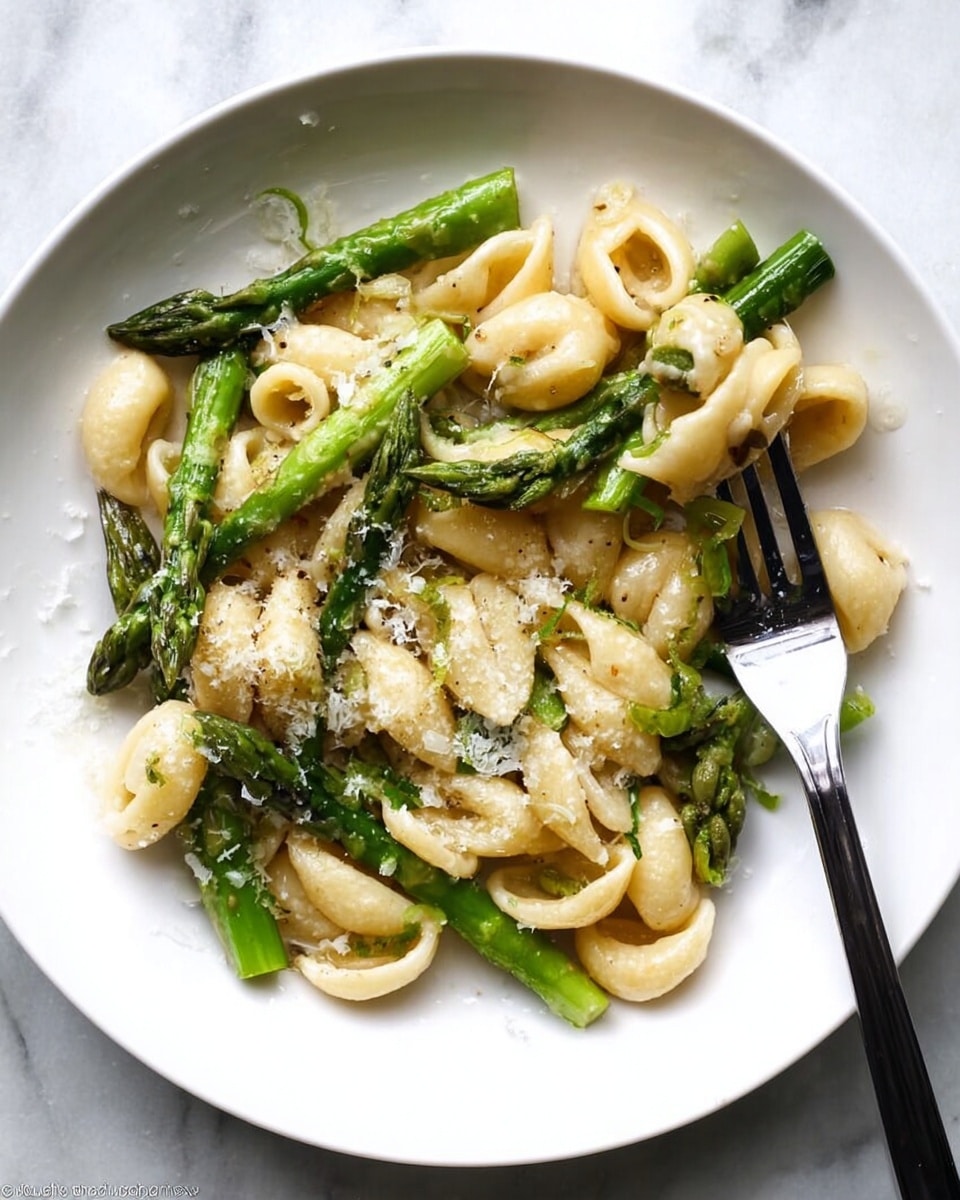 A white plate is filled with light beige curved pasta mixed with bright green asparagus pieces, some whole tips and some cut stalks, sprinkled lightly with grated white cheese. A black fork rests on the right side of the plate, piercing a piece of pasta. The background shows a white marbled surface. photo taken with an iphone --ar 4:5 --v 7