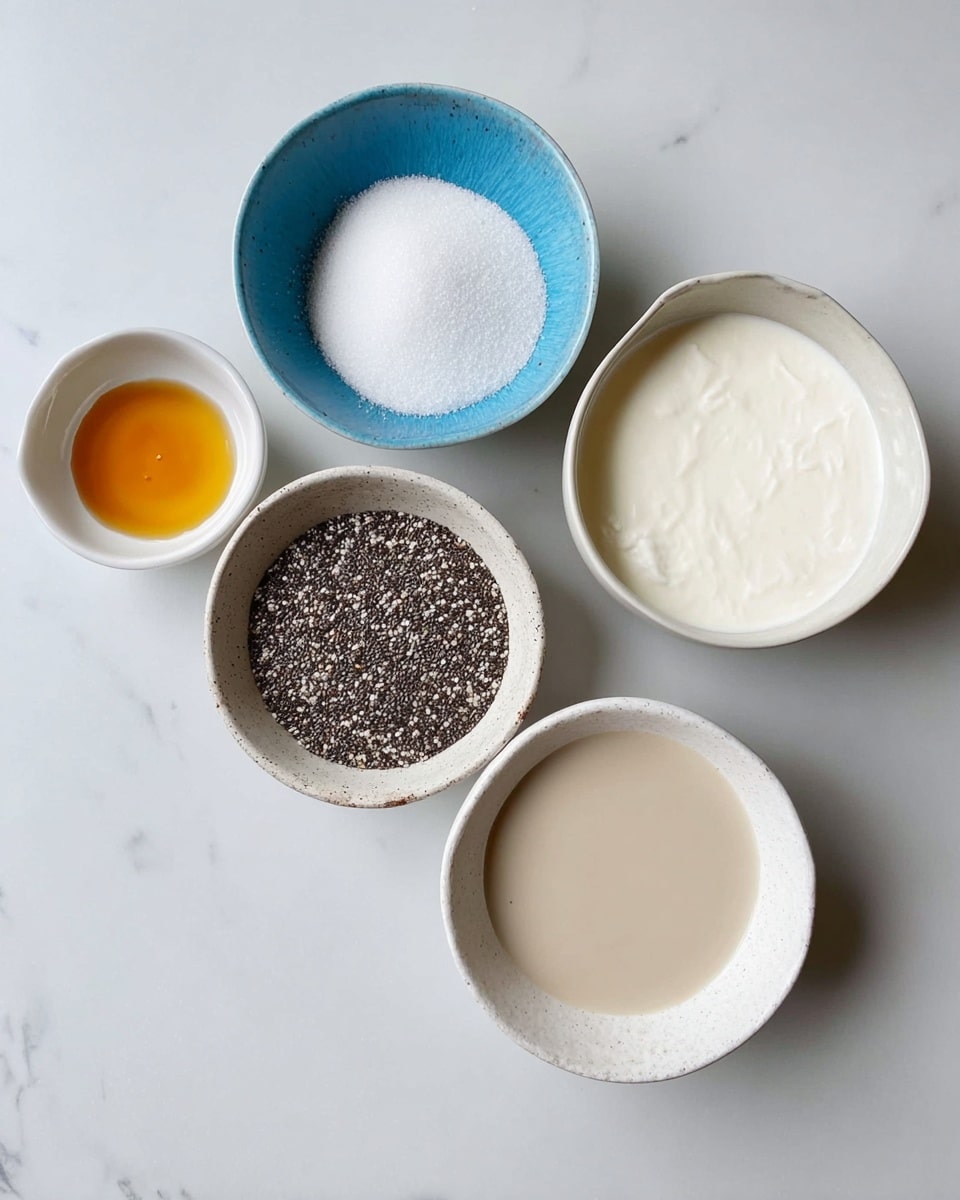 Five white bowls sit on a white marbled surface, arranged in a loose circle. The largest bowl at the bottom right holds a smooth, light beige liquid. To its left is a smaller bowl filled with tiny black and white chia seeds, speckled texture. Above this, a blue bowl contains white granulated sugar, smooth and fine. Next to it on the right, a white bowl holds thick, white coconut milk with a slightly chunky texture. The last bowl on the top left has a small amount of golden brown vanilla extract, shiny and clear. Photo taken with an iphone --ar 4:5 --v 7