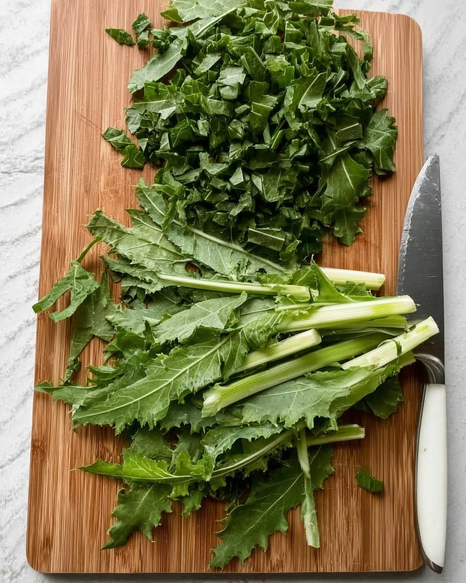 A wooden cutting board on a white marbled surface holds a pile of freshly chopped green leafy vegetables with jagged edges and pale green stems. The top half of the leaves is finely chopped into small pieces stacked loosely, while the bottom half shows larger whole leaves spread out. A silver knife with a white handle rests on the right side of the board near the chopped greens. photo taken with an iphone --ar 4:5 --v 7