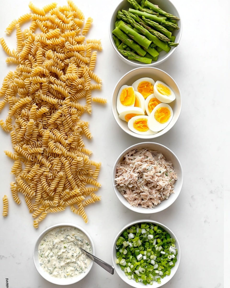 The image shows six items arranged on a white marbled surface. On the left side, there is a loose pile of uncooked spiral pasta. To the right, there are five white bowls placed in a loose vertical line. The top bowl contains chopped green asparagus, the second holds chopped hard-boiled eggs with yellow yolks and white parts, the third is filled with shredded tuna, the fourth bowl contains finely chopped green onions, and the bottom bowl has a creamy white sauce with green herbs, and a spoon resting inside. photo taken with an iphone --ar 4:5 --v 7