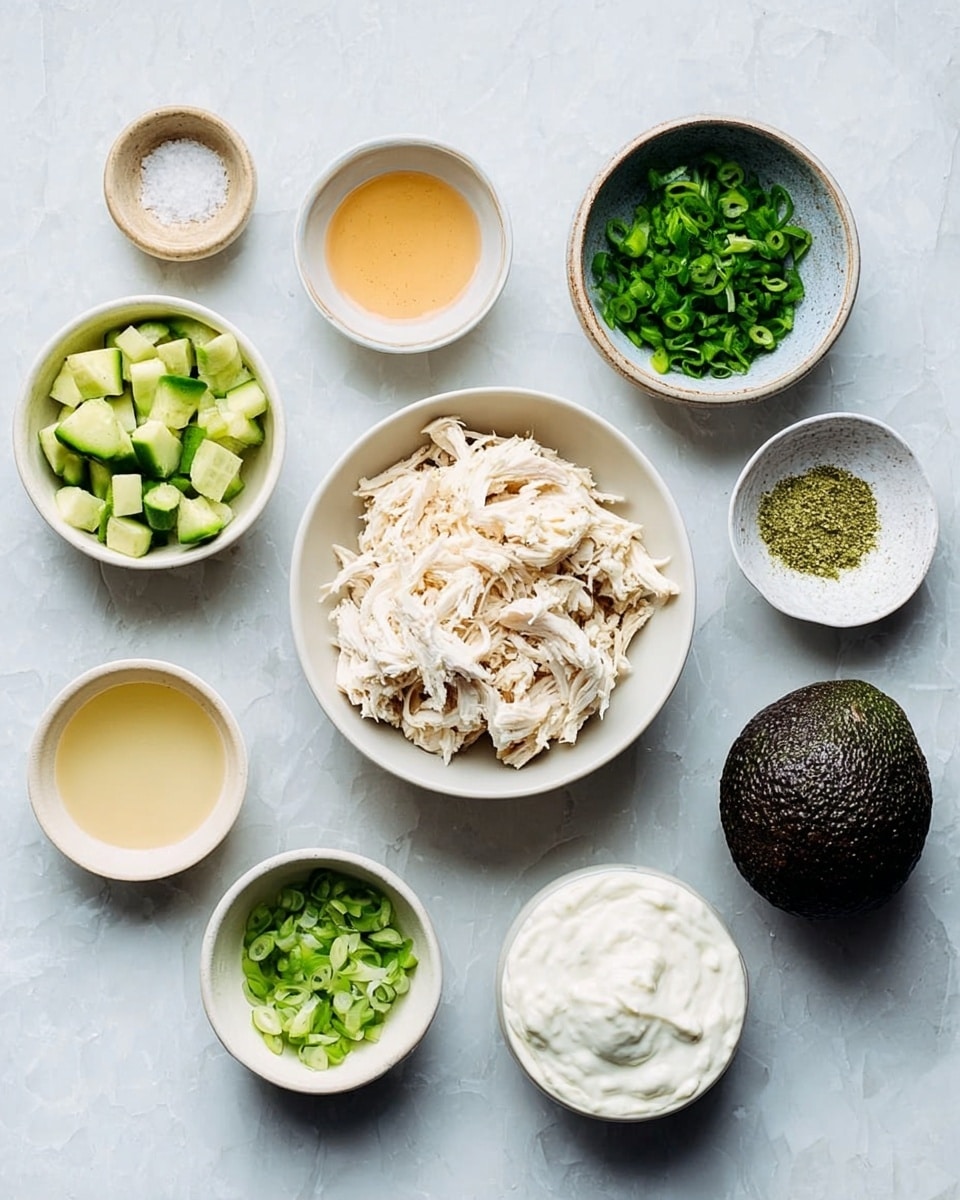 The image shows nine bowls and one avocado arranged on a white marbled surface. At the center is a white bowl filled with shredded pale chicken. Above it, a smaller white bowl holds chopped green herbs, and to the right another small white bowl with chopped green onions. Around these are other bowls including one with diced green cucumber, a small bowl of light yellow powder, one with a light brown liquid, another with a pale yellow liquid, and a small white bowl with coarse salt and pepper. To the far right is a white bowl filled with white creamy yogurt, and next to it a whole dark green avocado with a textured skin. photo taken with an iphone --ar 4:5 --v 7