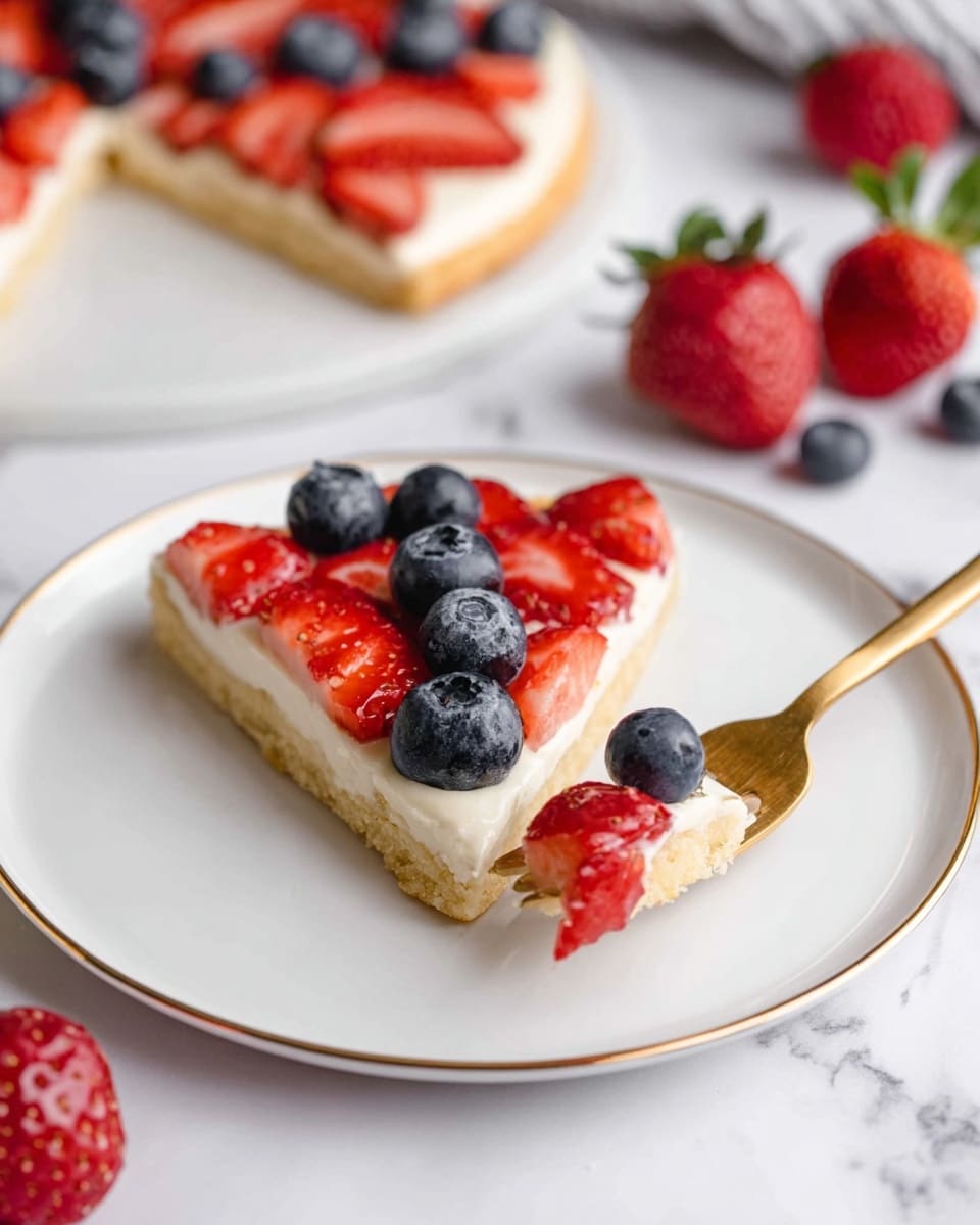 A slice of fruit pizza sits on a white plate with a thin gold edge, placed on a white marbled surface. The pizza has three visible layers: a light golden-brown base that looks soft and cakey, a smooth white cream layer spread evenly on top, and fresh fruit arranged on the cream. The fruit layer includes vibrant red strawberry halves and plump dark blue blueberries, placed in a neat pattern across the slice. A golden fork is picking up a small piece from the slice that has three blueberries on top. In the background, parts of the whole fruit pizza and scattered strawberries and blueberries add color to the scene. Photo taken with an iphone --ar 4:5 --v 7