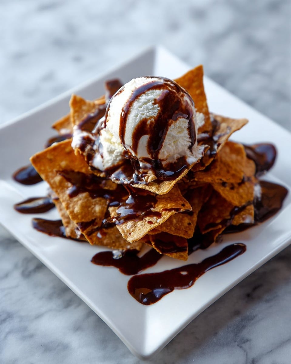 A white square plate holds a pile of golden brown crispy tortilla chips arranged in layers, creating a textured base. On top of the chips, there is a scoop of white ice cream with a smooth and slightly melting texture. Dark chocolate sauce is drizzled generously over both the ice cream and chips, creating glossy, rich streaks and small pools on the plate. The plate is set on a white marbled surface. photo taken with an iphone --ar 4:5 --v 7