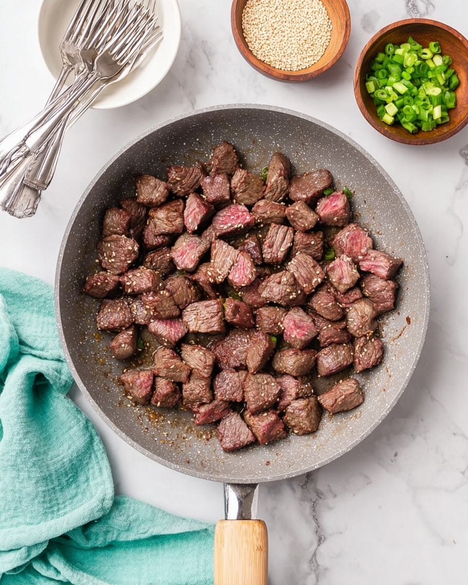 A round metal pan filled with a single layer of cooked ground beef mixed with small pieces of translucent cooked onion, showing a crumbly brown and light tan texture evenly spread across the pan. The pan is placed on a white marbled surface, partially covering a white cloth with blue stripes, with a wooden spatula resting nearby. Photo taken with an iphone --ar 4:5 --v 7