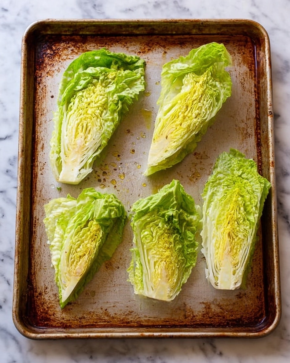 The image shows four wedges of iceberg lettuce placed on a rectangular, well-used baking tray with a brownish tint from repeated use, all sitting on a white marbled surface. Each wedge has layers of light green and pale yellow leaves tightly packed, the texture looking fresh and crisp. The wedges are spaced evenly, and there is a light drizzle of oil visible on the lettuce and tray, adding a slight shine. The tray’s surface has a rough, rustic appearance with darker and lighter spots showing age and frequent use. Photo taken with an iphone --ar 4:5 --v 7