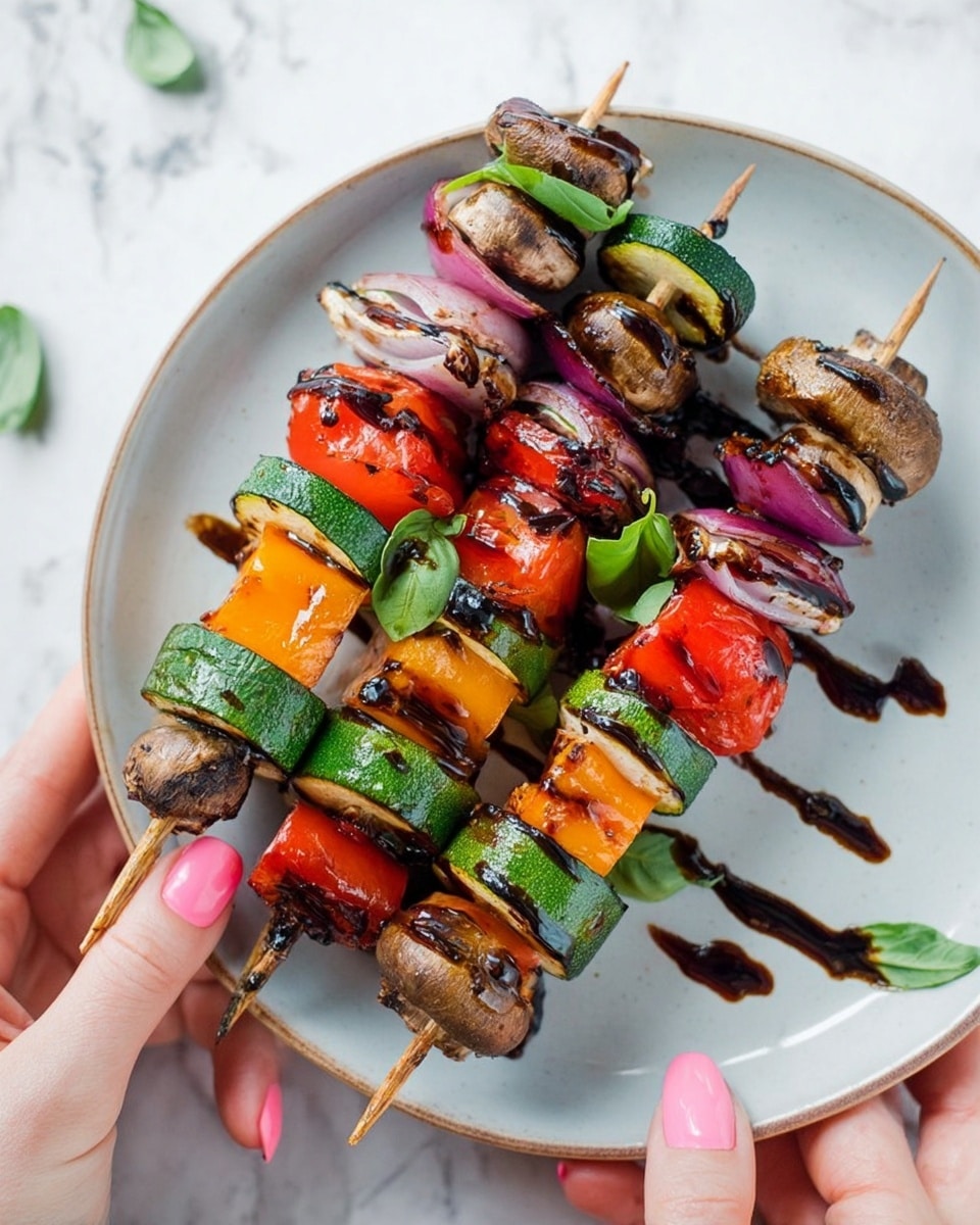 Three vegetable skewers lay on a white plate with a white marbled surface underneath. Each skewer is made of several layers starting with thick green zucchini slices with a smooth, firm texture. This is followed by rings of purple-red onion with a slightly shiny surface, then bright red cherry tomatoes, firm orange bell pepper cubes, green bell pepper pieces, and whole brown mushrooms with a slightly wrinkled texture. A dark glaze, possibly balsamic, is drizzled artfully over the skewers with small green basil leaves placed on top. A woman's hand is holding one skewer from the left side, showing neatly painted pink nails, and another woman's hand supports the plate at the bottom right corner. photo taken with an iphone --ar 4:5 --v 7