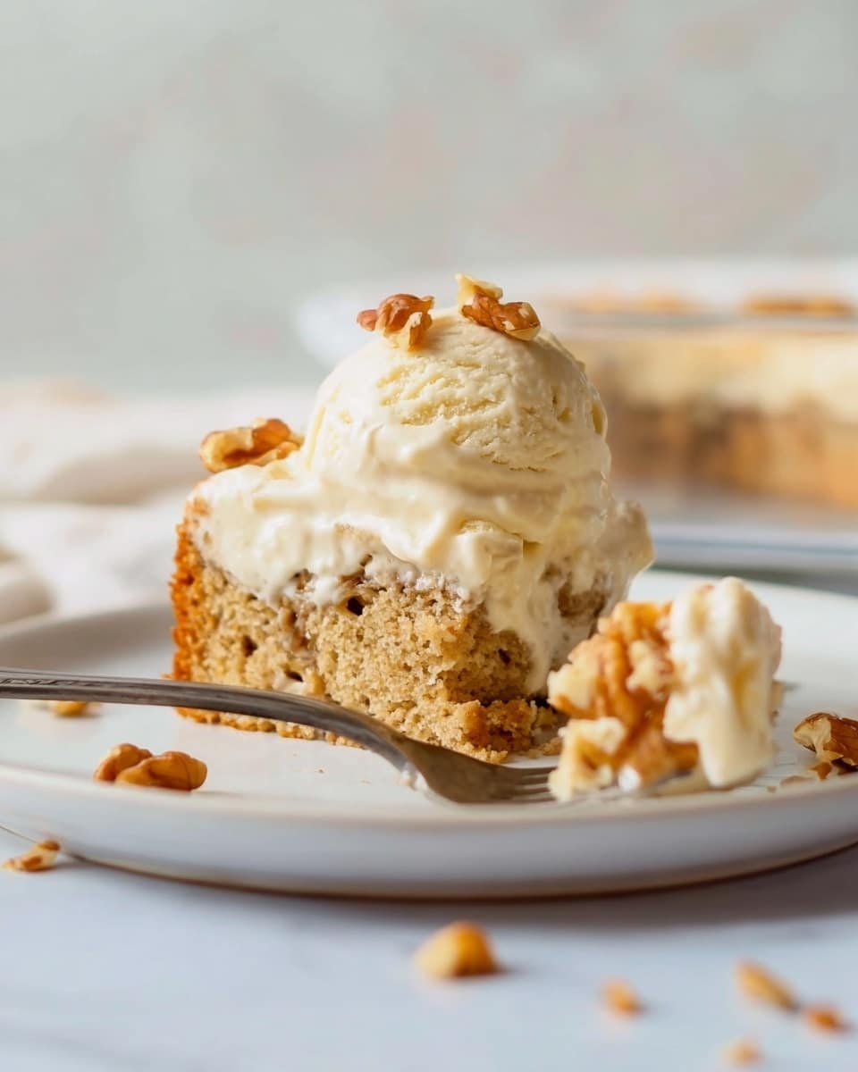 The image shows a piece of cake on a white plate with a white marbled background. The cake has two layers: a light brown layer with small nuts inside at the base, topped with a scoop of creamy white ice cream. There are small pieces of walnut scattered around the plate, and a fork with a piece of cake and ice cream is placed in front of the cake. A woman's hand is holding the fork. The cake looks soft and moist, and the ice cream is smooth and slightly melting on top. Photo taken with an iphone --ar 4:5 --v 7