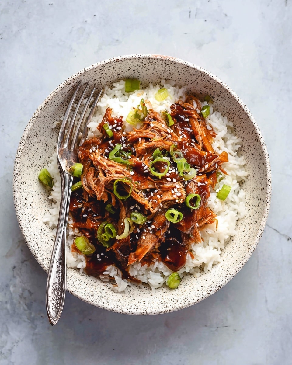 A white speckled shallow bowl is filled with two main layers: the bottom layer is a bed of fluffy white rice with a soft texture, and the top layer is a pile of shredded dark brown cooked jackfruit, glazed with a shiny sauce. The jackfruit is garnished with thin slices of bright green scallions and sprinkled with small white sesame seeds. A silver fork and knife are placed together, resting on the left side of the bowl. The whole scene is set against a white marbled surface photo taken with an iphone --ar 4:5 --v 7