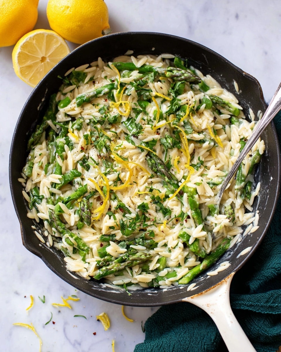 The image shows two white bowls filled with a creamy orzo pasta mixed with bright green asparagus and herbs, topped with lemon zest and black pepper. Behind the bowls is a black pan holding more of the creamy orzo and asparagus mix, with a silver spoon resting inside. To the left, a lemon is cut in half, and a green cloth is partially visible on a white marbled surface. The dish’s layers include creamy light sauce, small orzo pasta pieces, and tender asparagus tips, all mixed together with fresh herb bits giving a fresh green color contrast. photo taken with an iphone --ar 4:5 --v 7