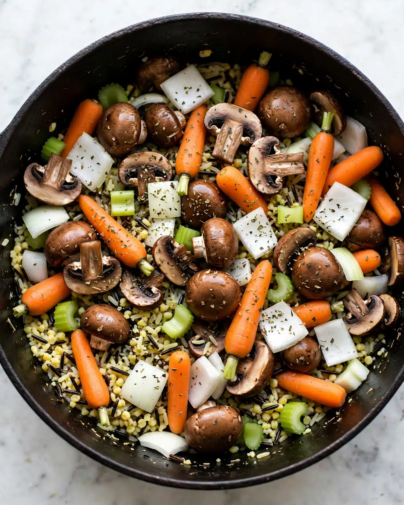 Crockpot Herb Butter Chicken and Wild Rice Recipe 4 The image shows a mix of fresh ingredients inside a dark round pot, placed on a white marbled surface. There are whole and sliced brown mushrooms with a smooth, shiny texture. Bright orange baby carrots are scattered among white onion pieces and small green celery chunks. The dish also contains a layer of wild rice mixed with some light yellow grains. Everything is sprinkled lightly with dried herbs, giving a speckled look of dark green and brown on the colorful vegetables and rice. Photo taken with an iphone --ar 4:5 --v 7